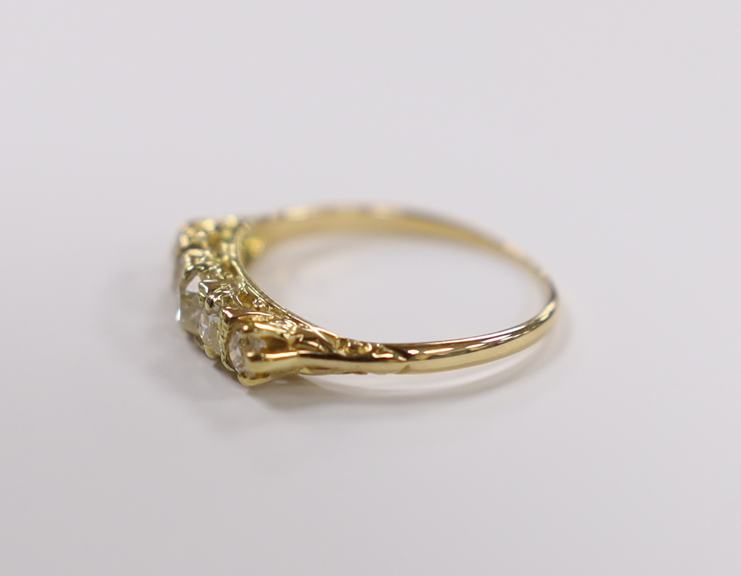 An early 20th century yellow metal and graduated five stone old round diamond set half hoop ring, size M, gross weight 2 grams.